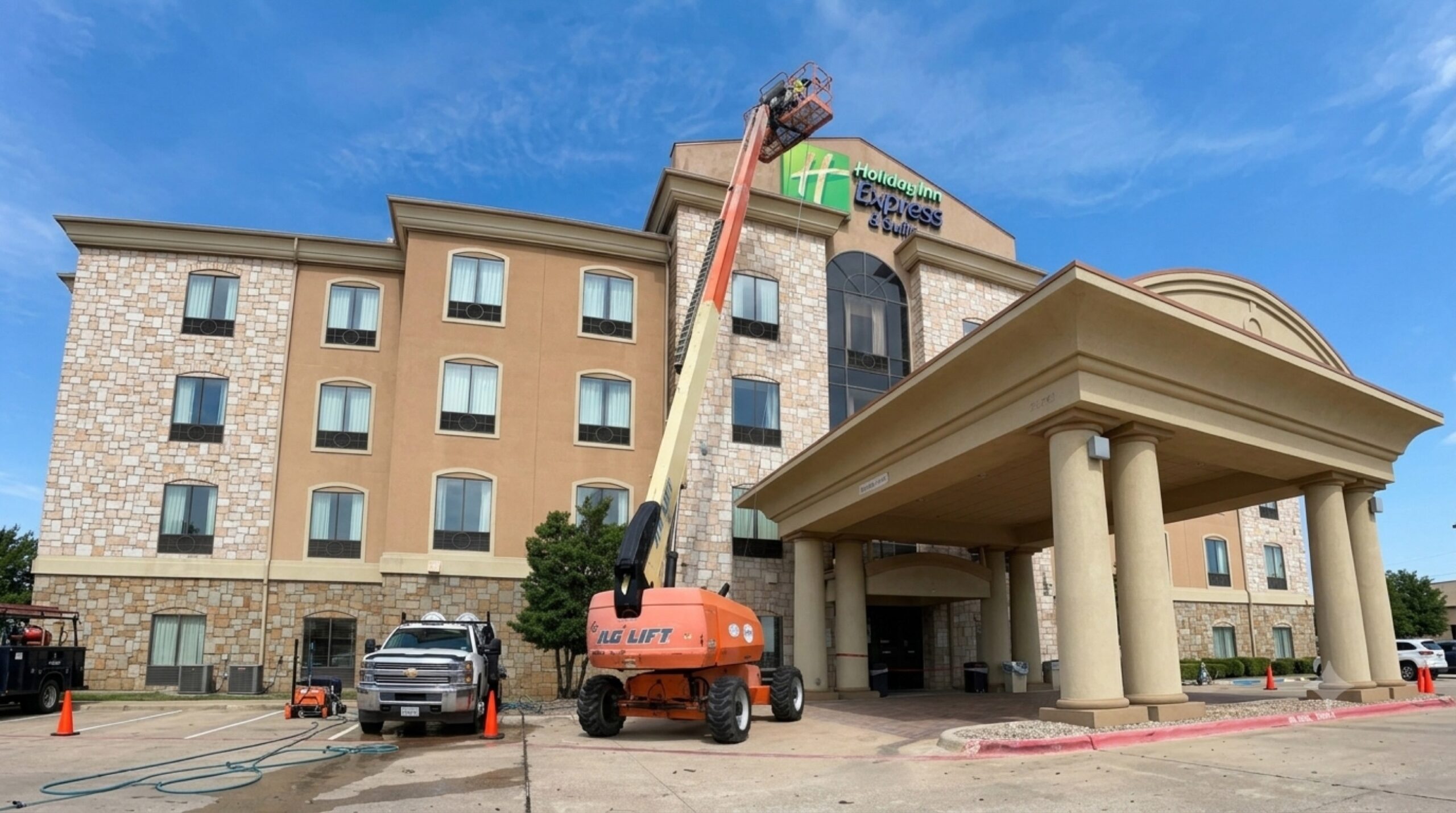 NETX Softwash boom lift extended to the roofline of a commercial hotel property